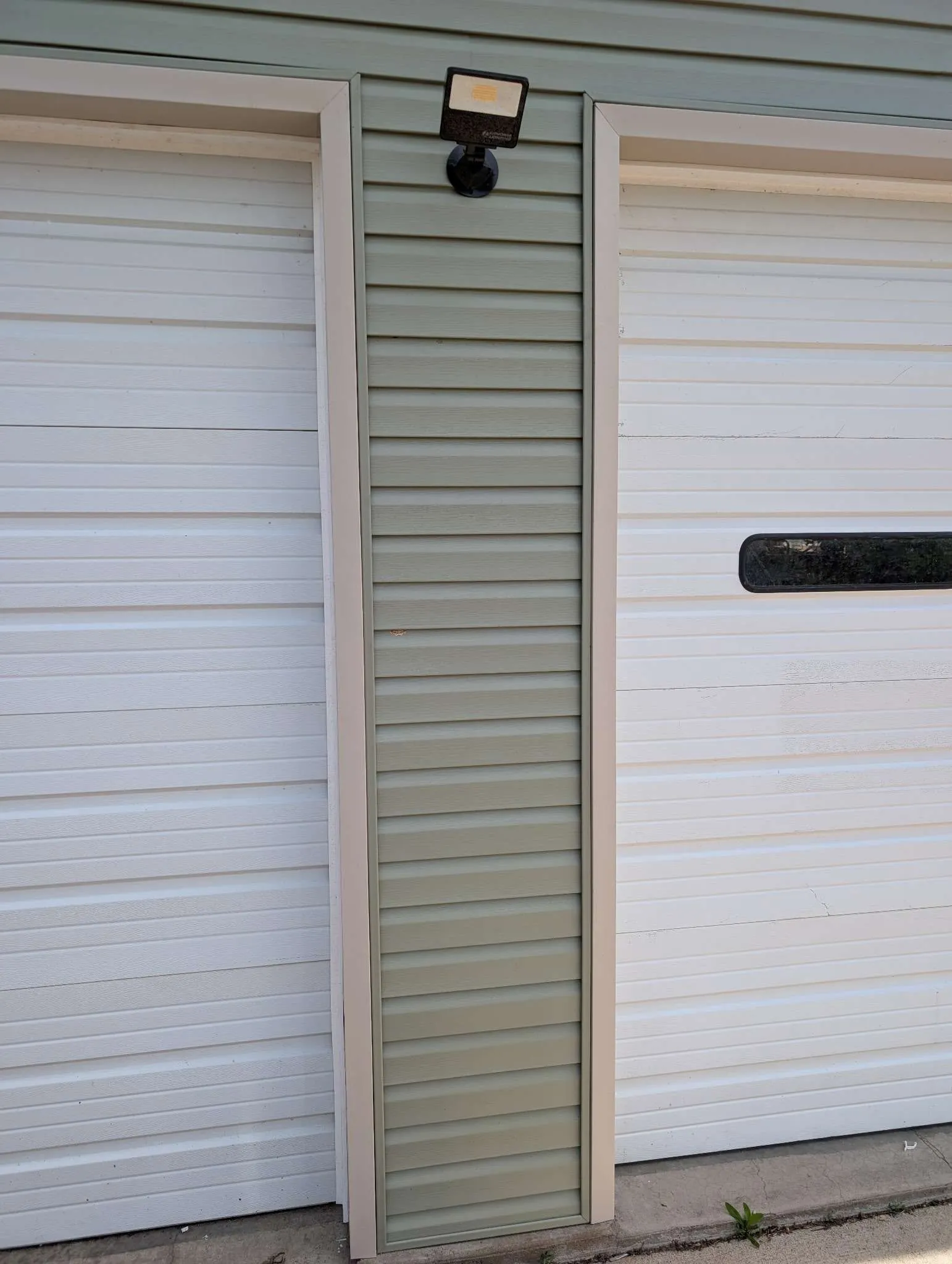 Close-up siding detail between garage doors with exterior light fixture